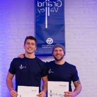 Students posing with their I am GV certificates in front of blue lights.